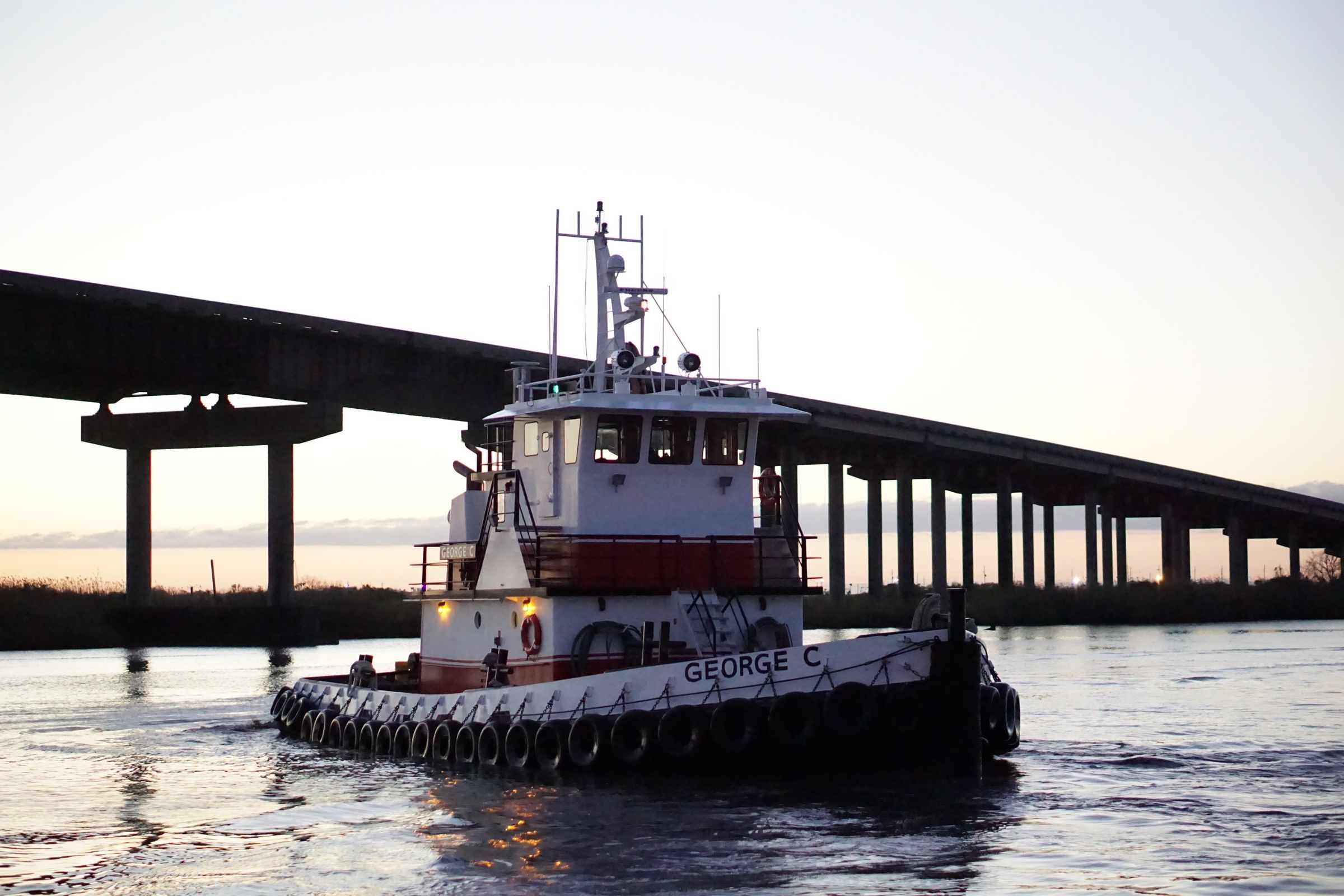 M/V George C underway beneath a highway bridge at golden hour